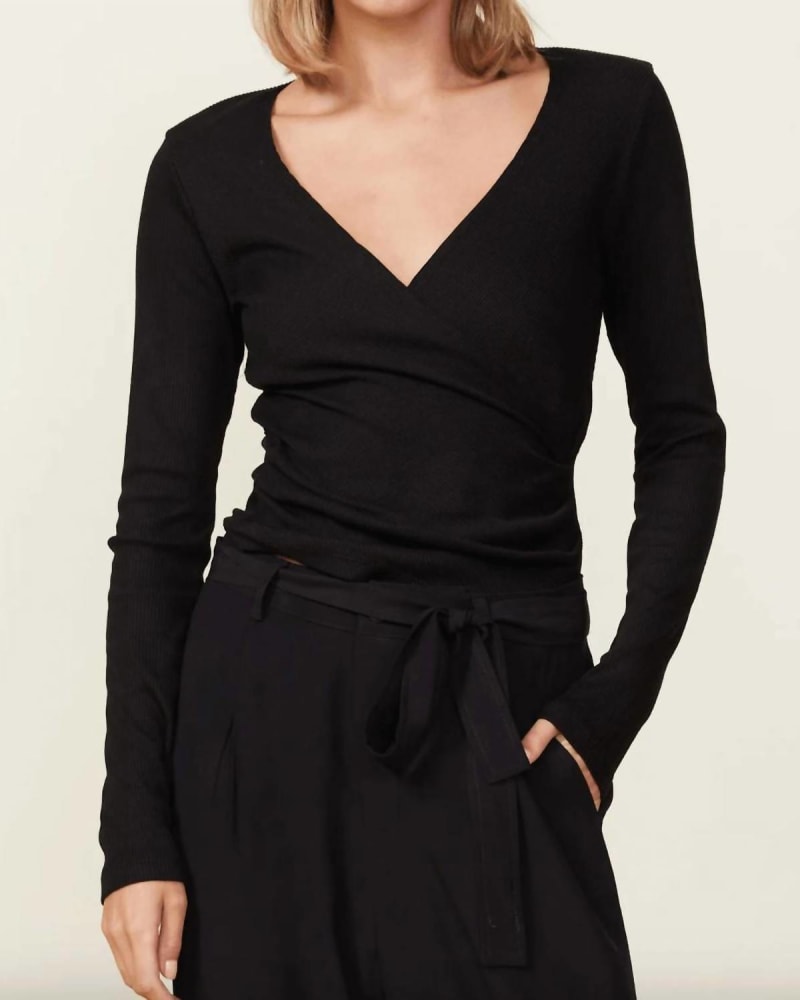 Front of a model wearing a size L Rib Long Sleeve Wrap Top in Black in Black by MONROW. | dia_product_style_image_id:346294